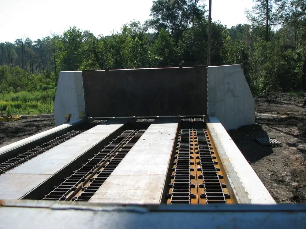 Concrete industrial conveyor outdoors with trees in background.