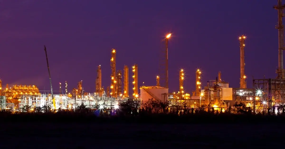 Industrial plant illuminated against dark night sky.
