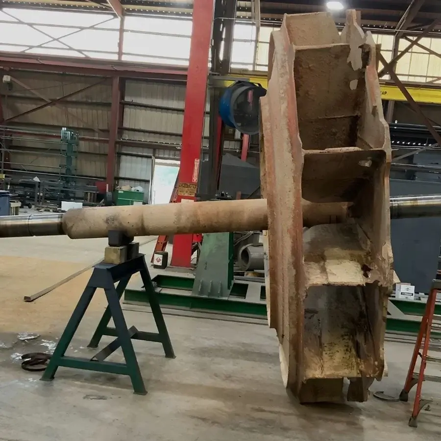 Rusty industrial fan component positioned on metal stand.