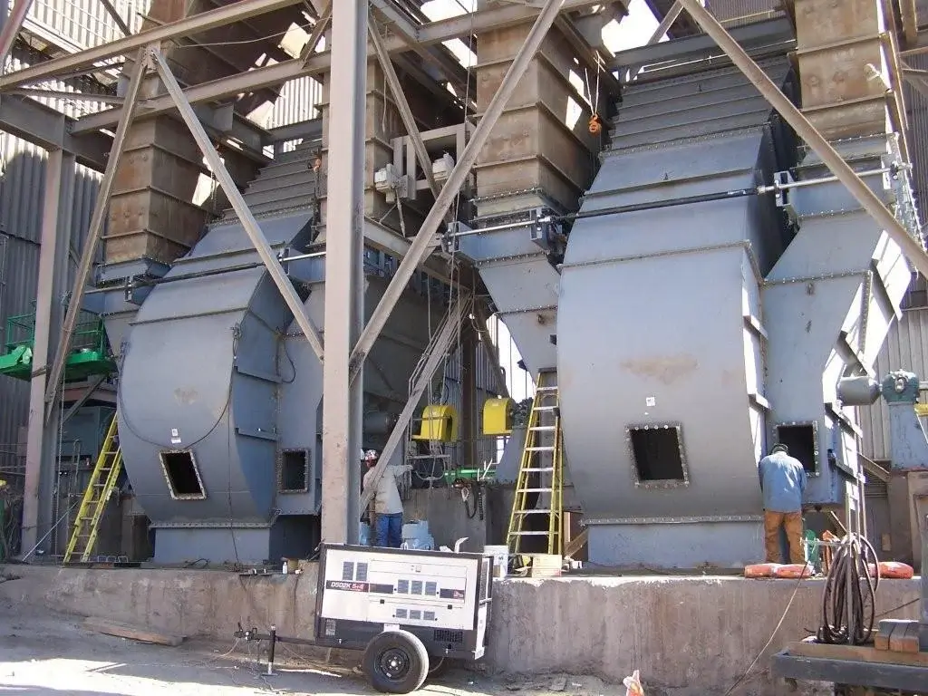 Large industrial fans with ladders and workers onsite.