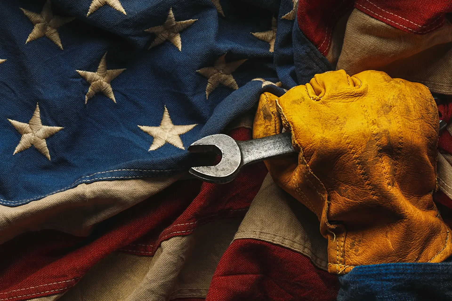 Gloved hand holding wrench on American flag.