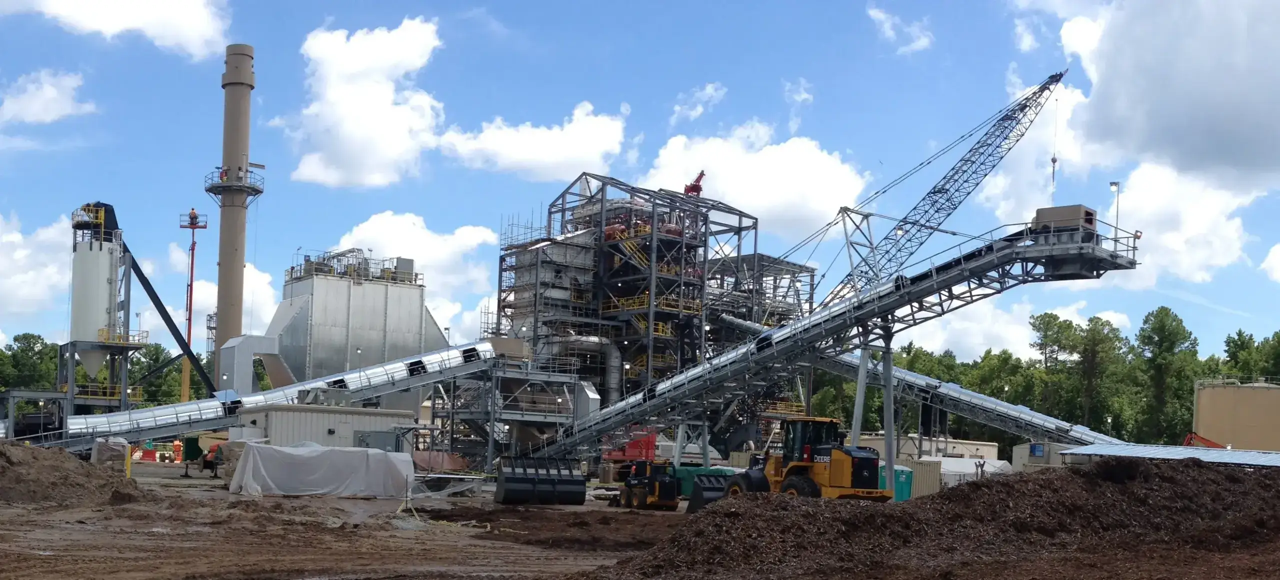 Industrial facility with cranes and conveyors under blue sky.