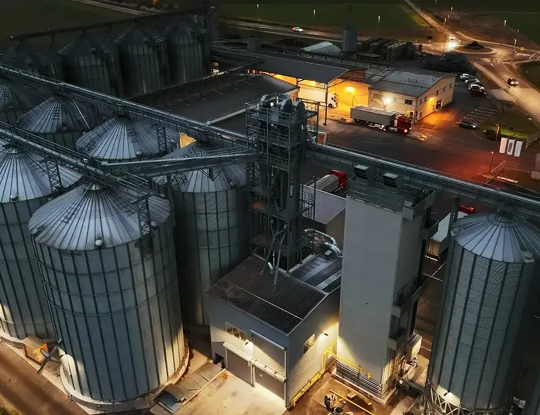 Industrial facility with illuminated silos at dusk.