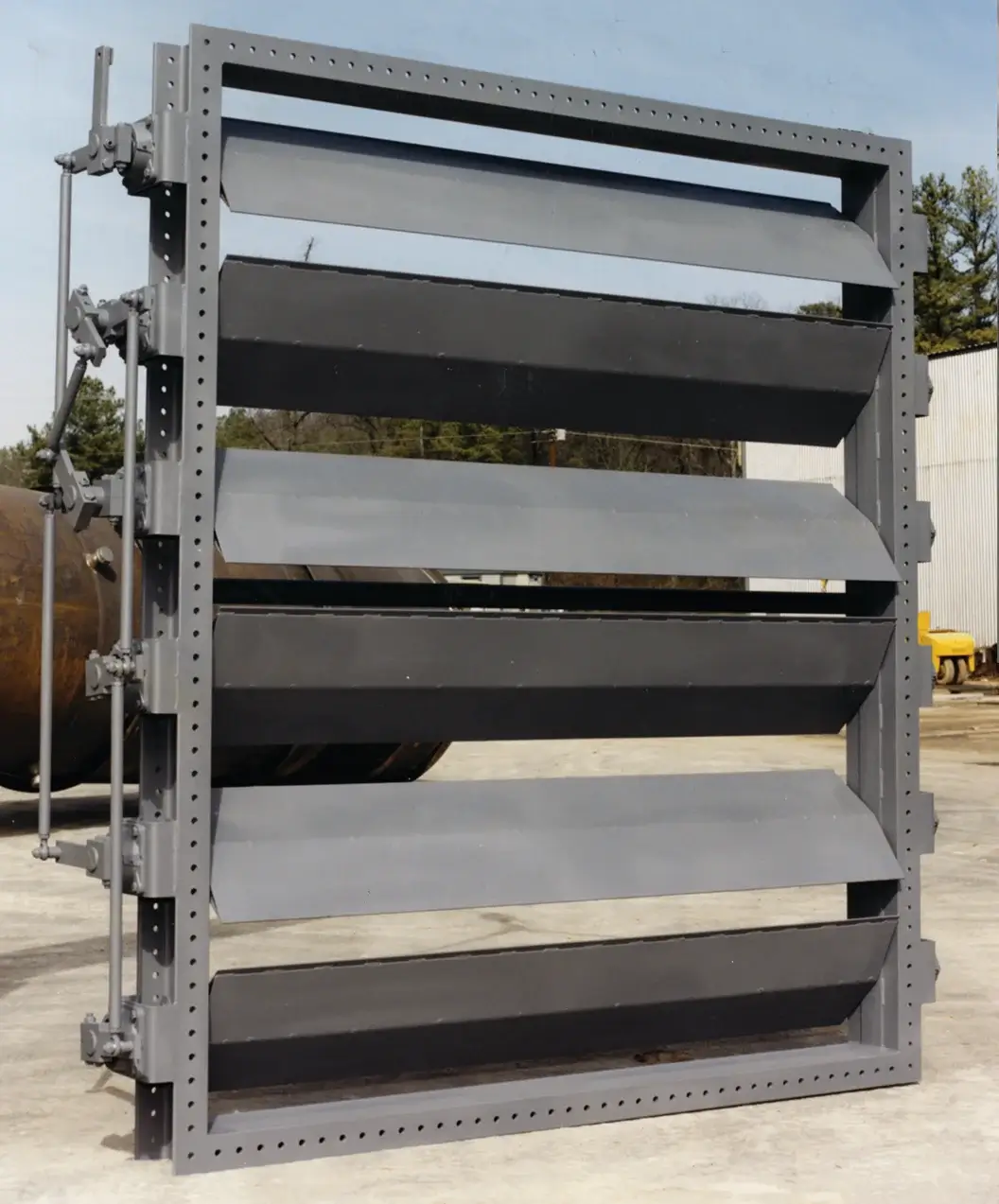 Large industrial louver system outdoors on concrete surface.