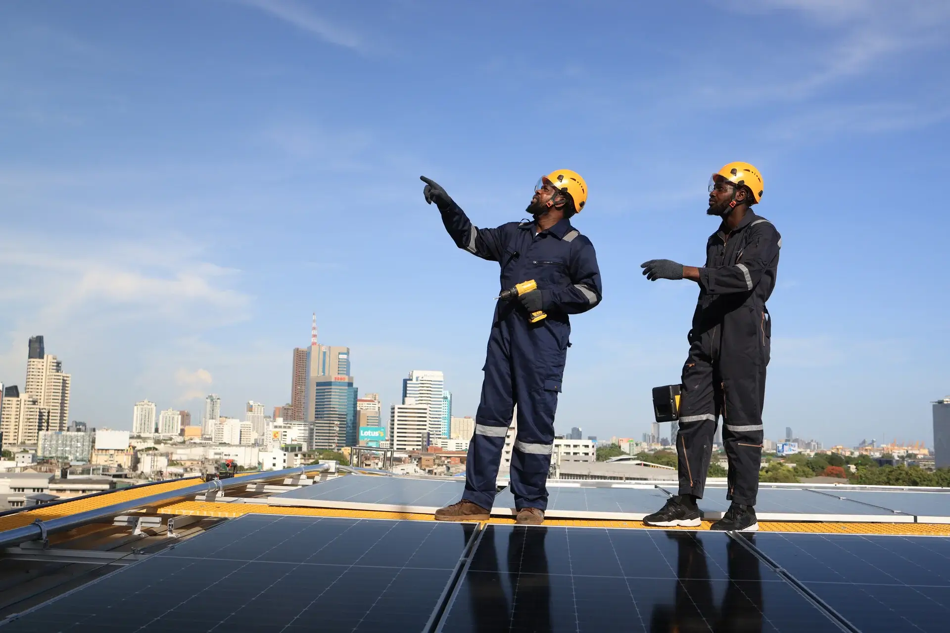 Workers in protective gear discussing on rooftop.