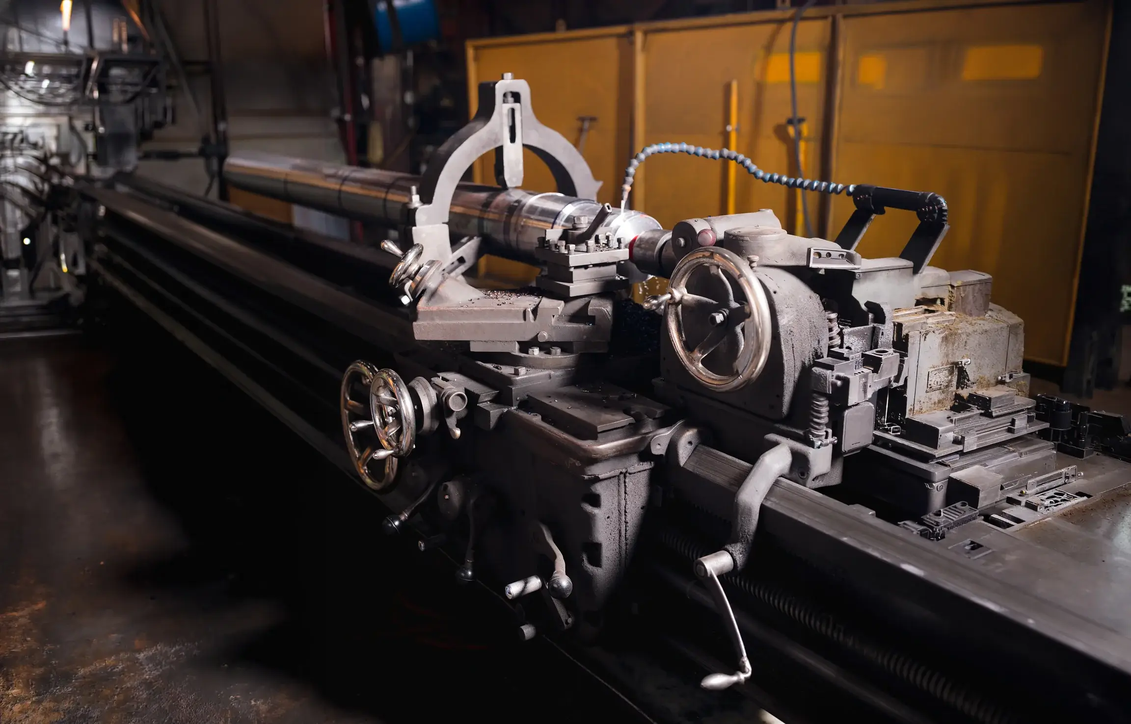 Industrial lathe machine operating in dimly lit workshop.