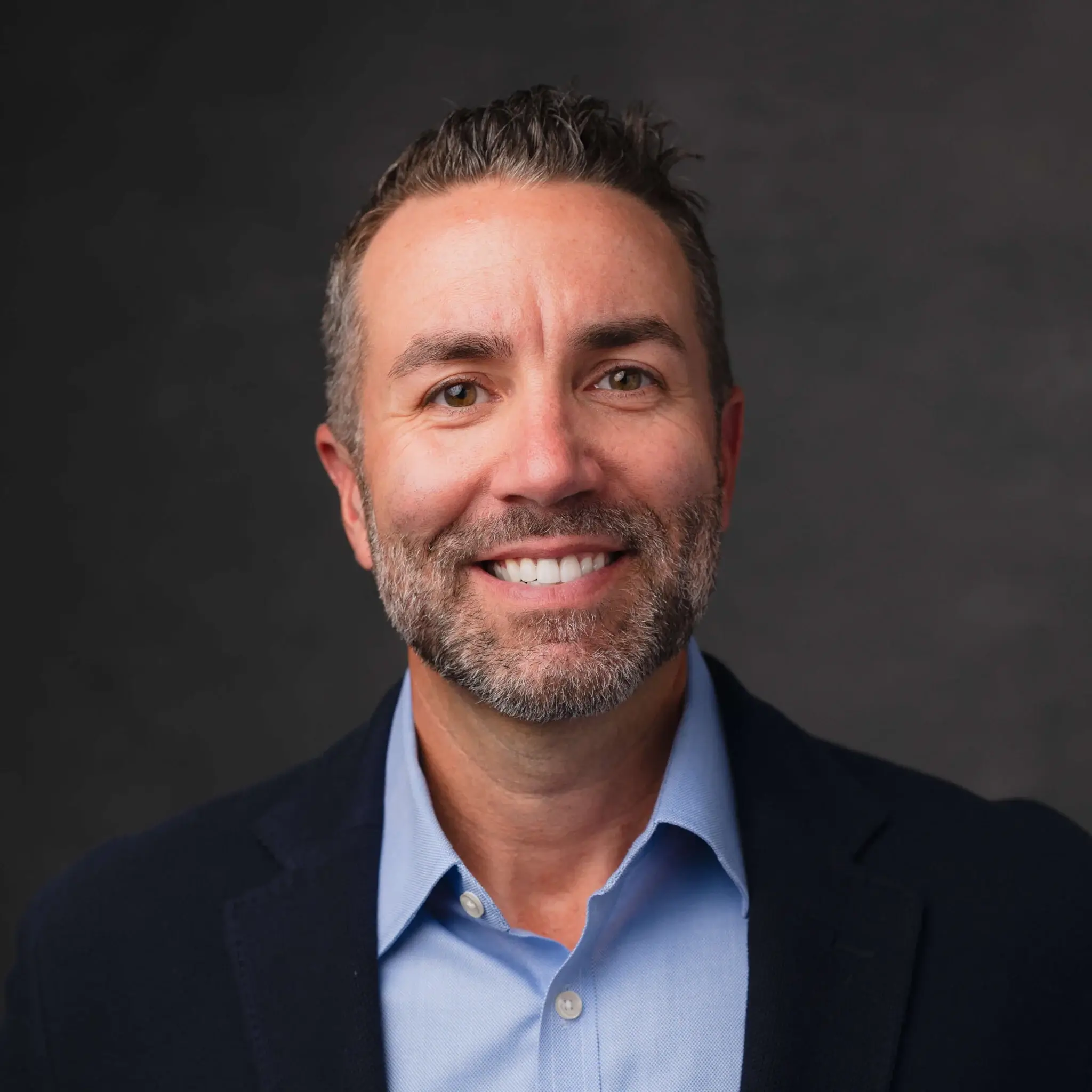 Smiling man in a blazer and blue shirt.