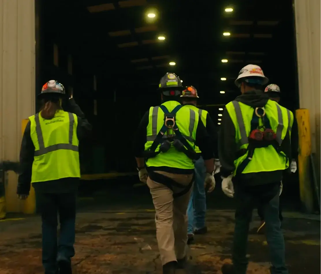 Workers in safety gear entering industrial facility.