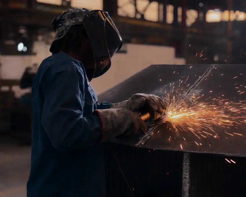 Welder creating sparks in industrial setting.