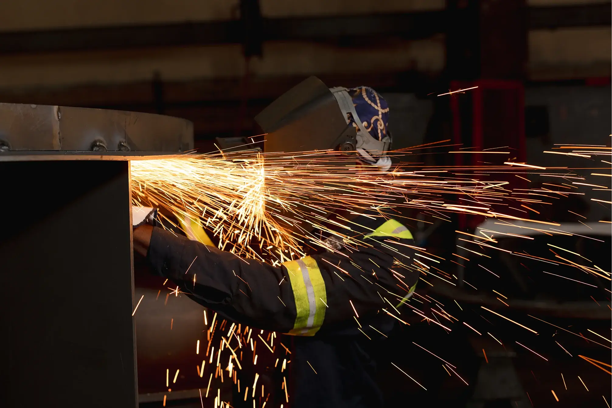 Welder sparks fly during metalwork in industrial setting.