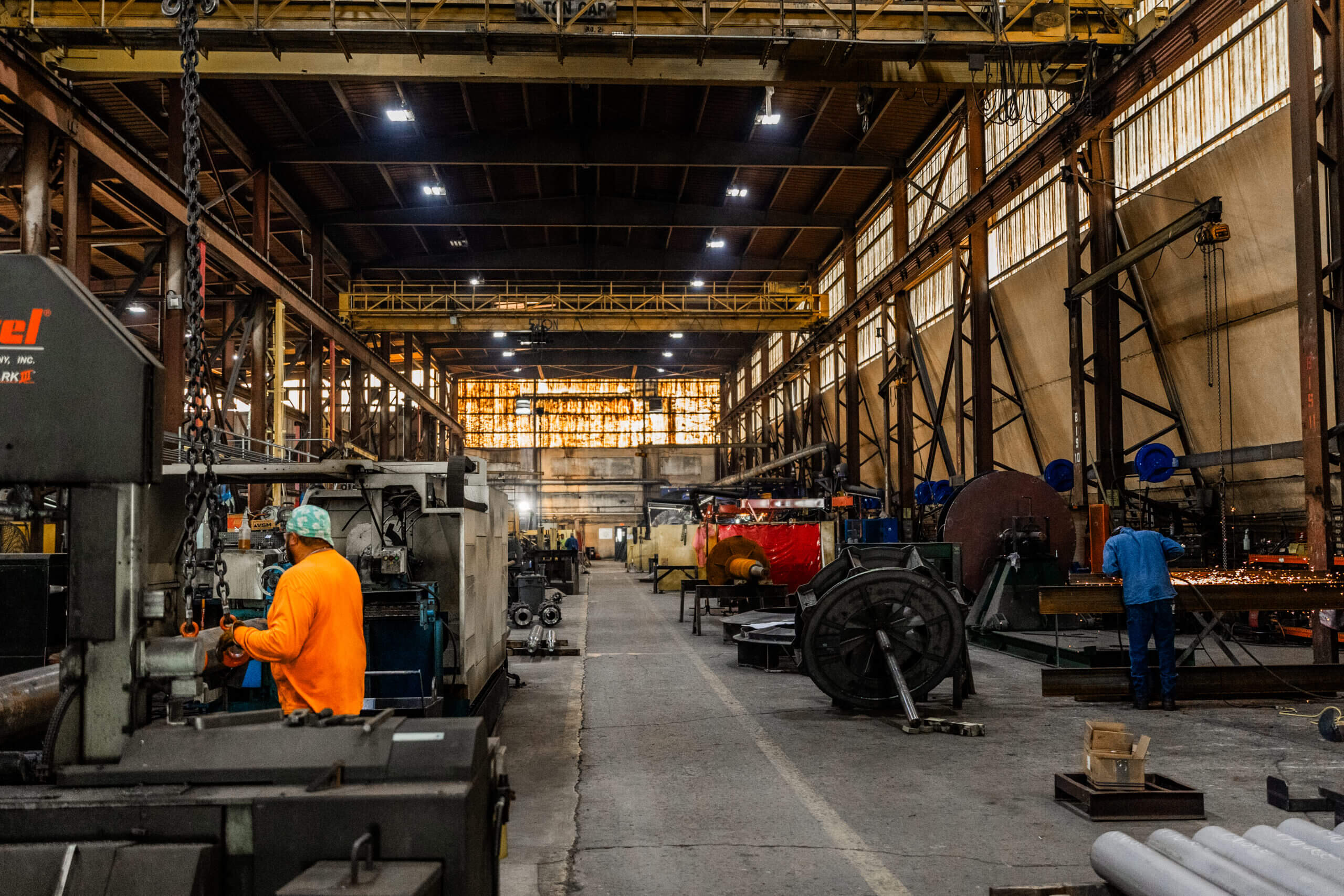 Workers operating machinery in large industrial warehouse.