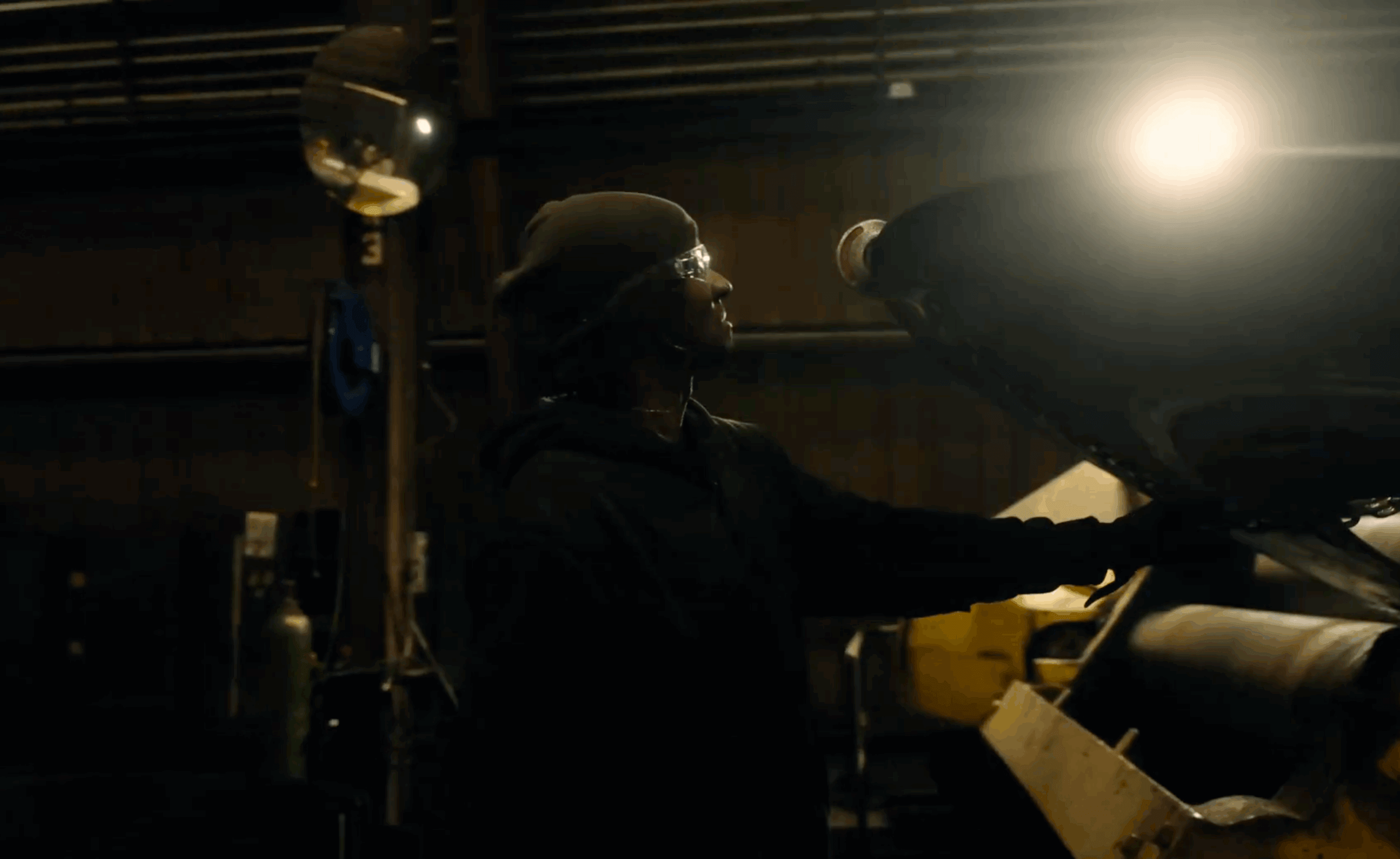 Worker adjusting machinery under bright industrial light.