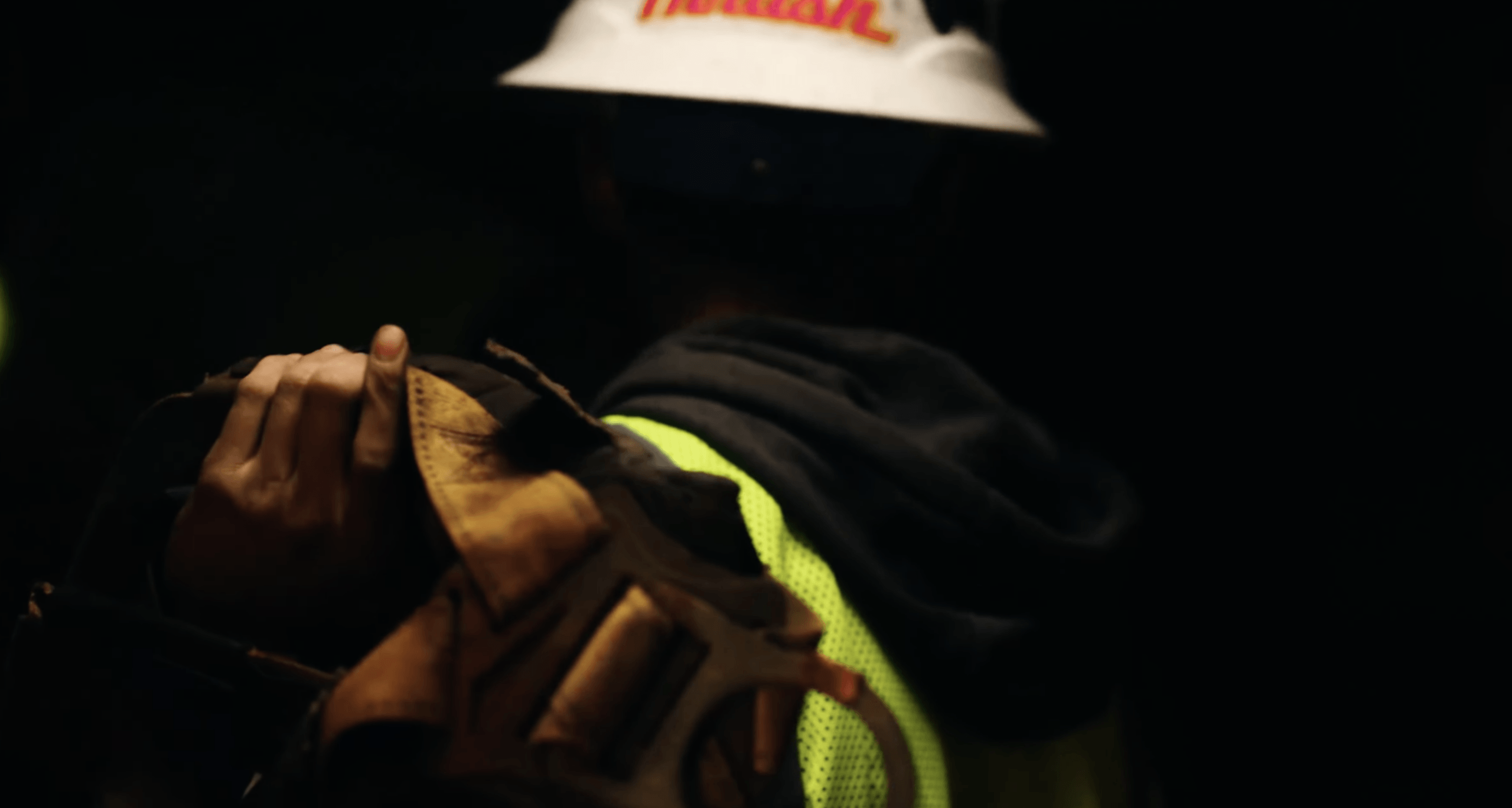 Worker carrying tools, wearing reflective safety gear.