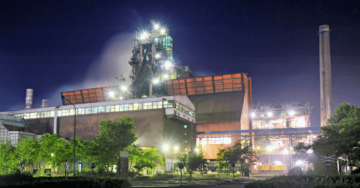 Industrial plant illuminated at night with bright lights.