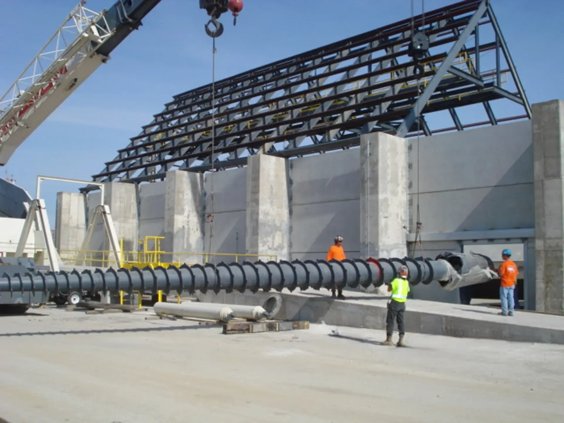 Workers install large industrial screw conveyor.