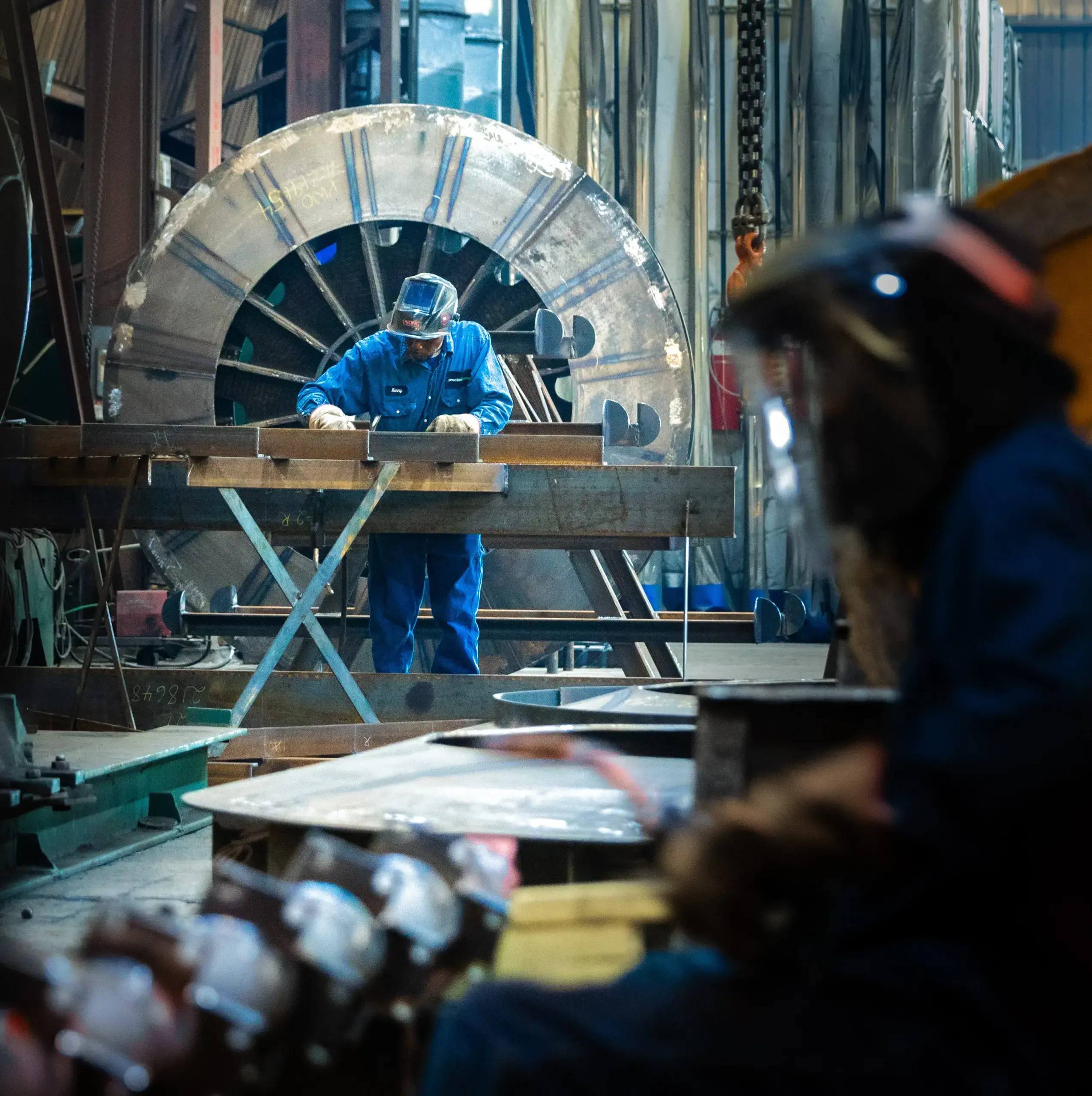 Worker welding metal in an industrial workshop.