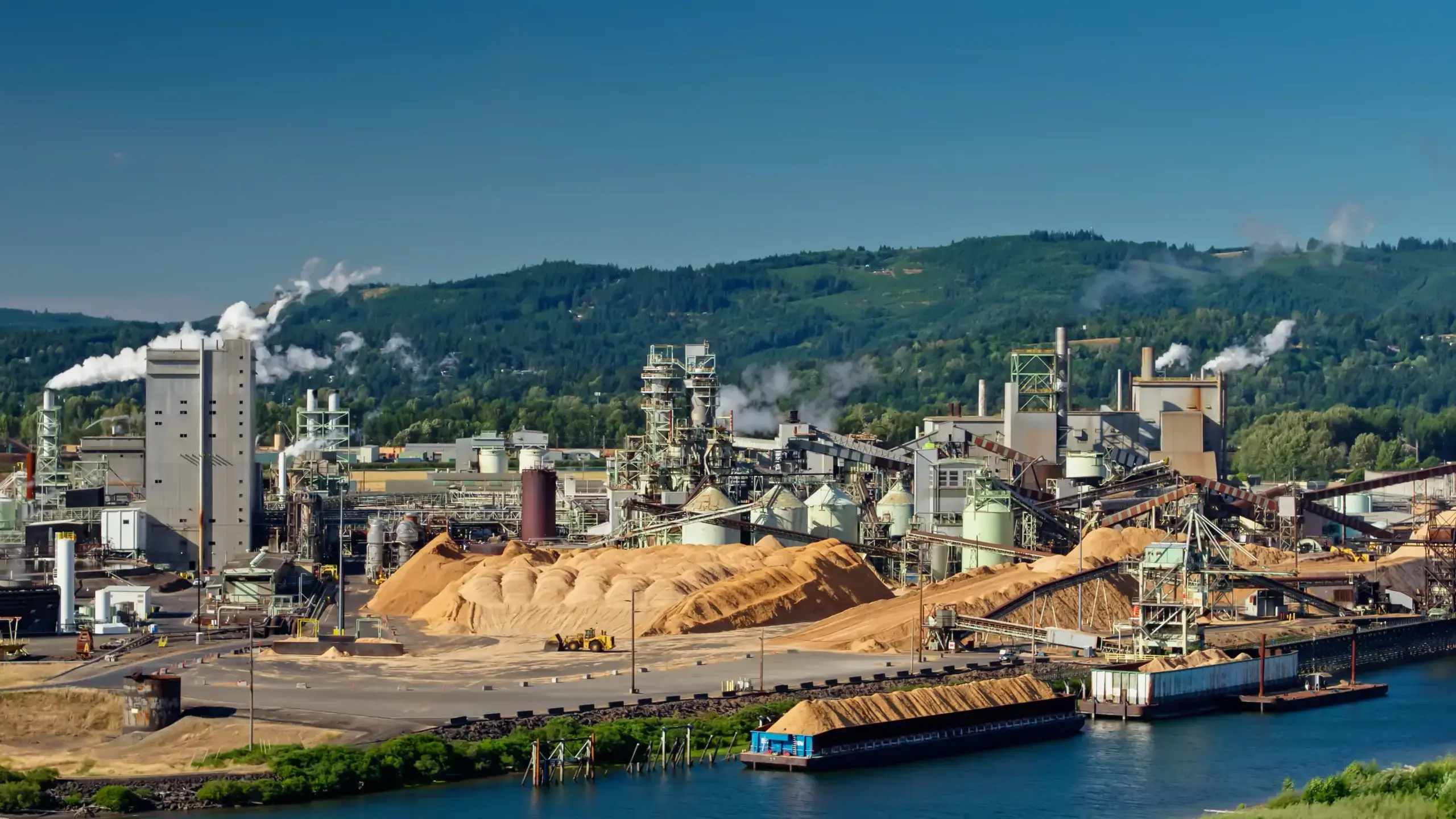 Industrial facility with wood piles and large machinery.