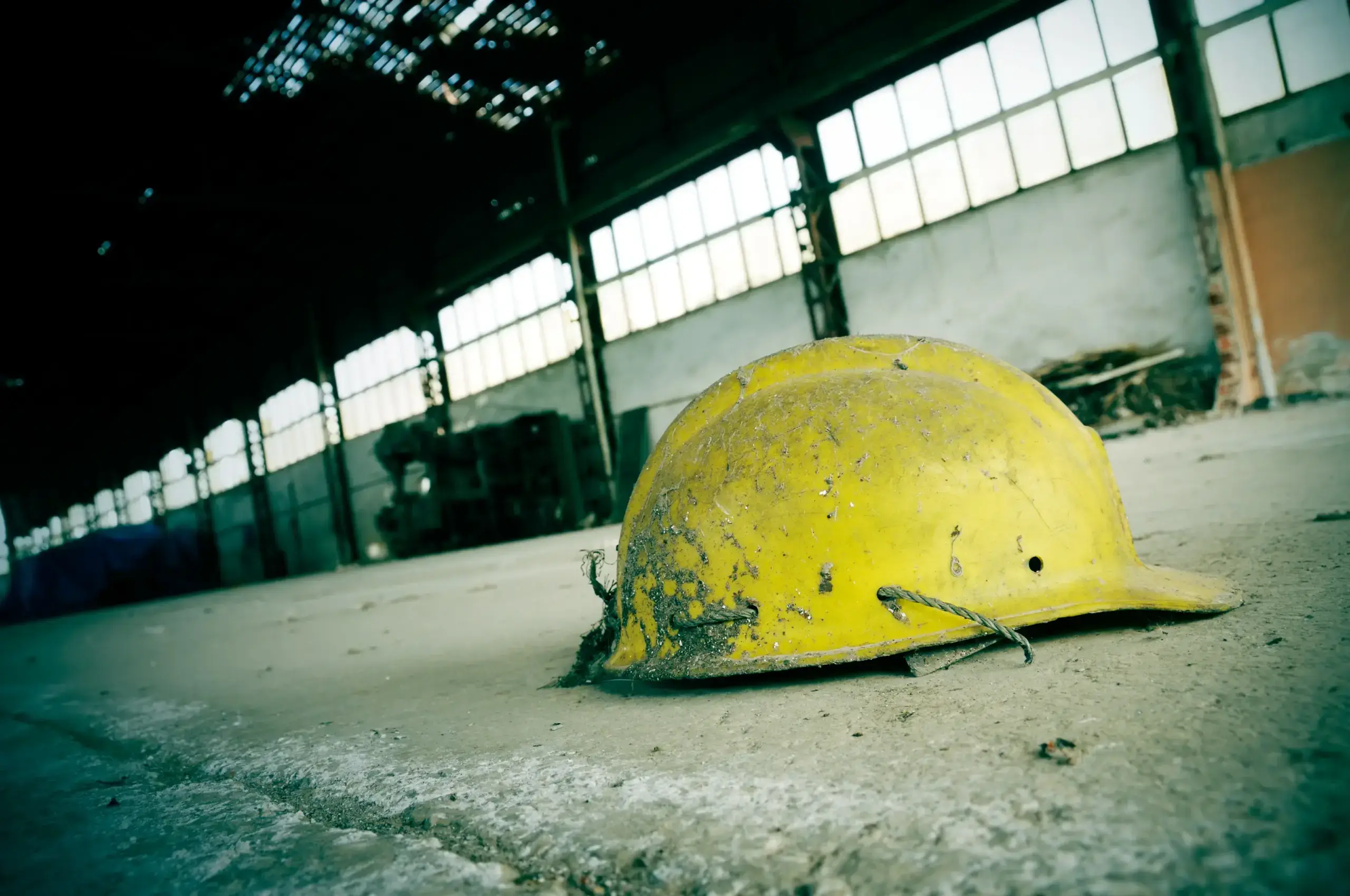 Yellow hard hat on dusty factory floor.