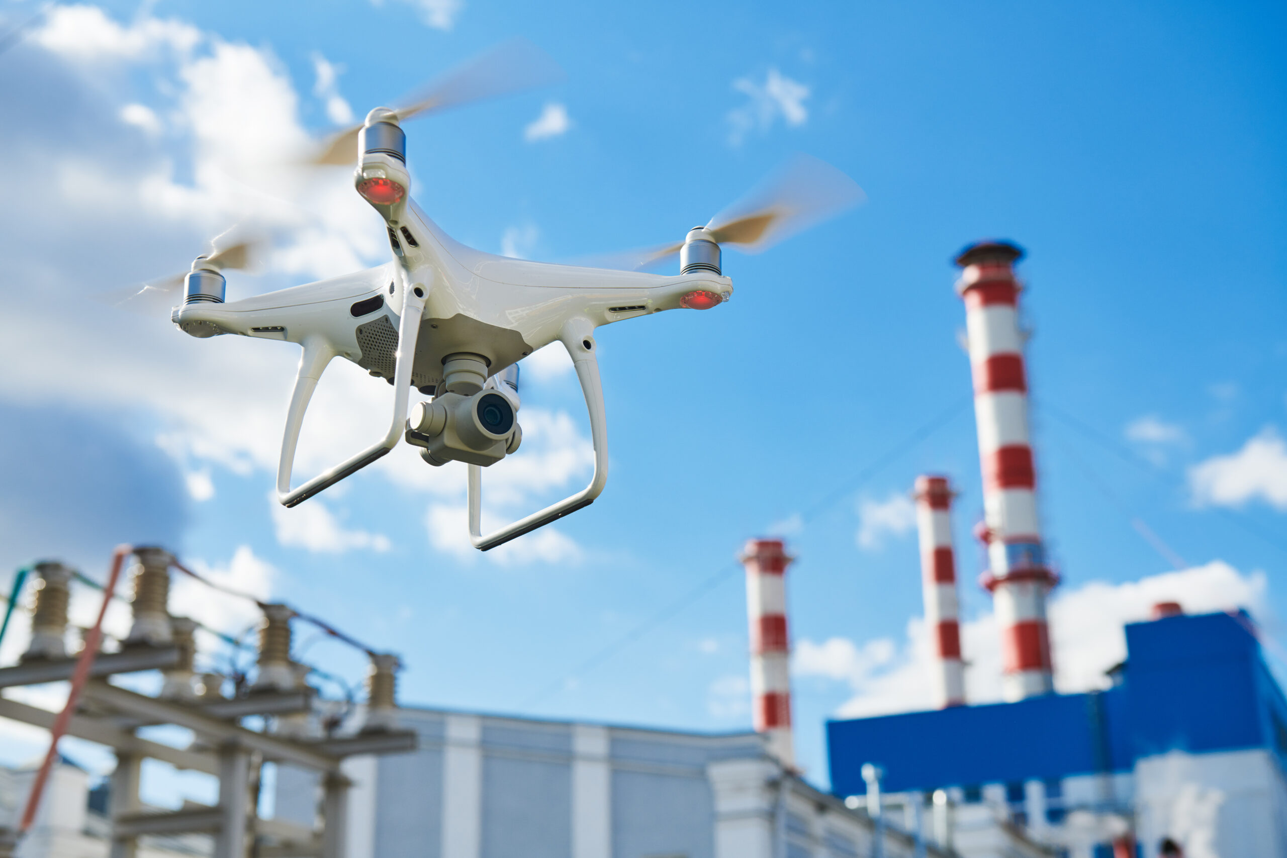 drone in midflight flying over an industrial manufacturing plant